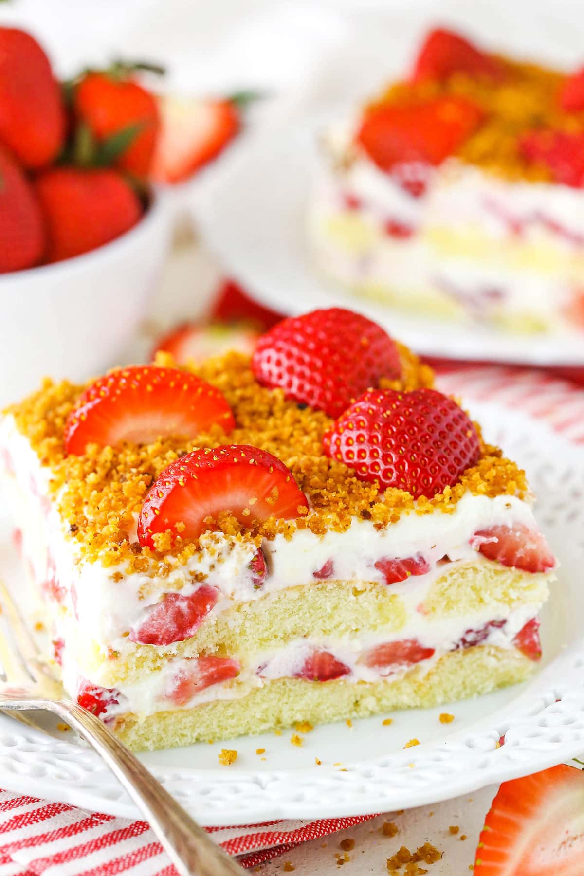 This strawberry icebox cake is an easy dessert idea for summer! Made with fresh strawberries, a berry cream filling, and ladyfinger cookies. Slice of strawberry cake with berry cream filling.