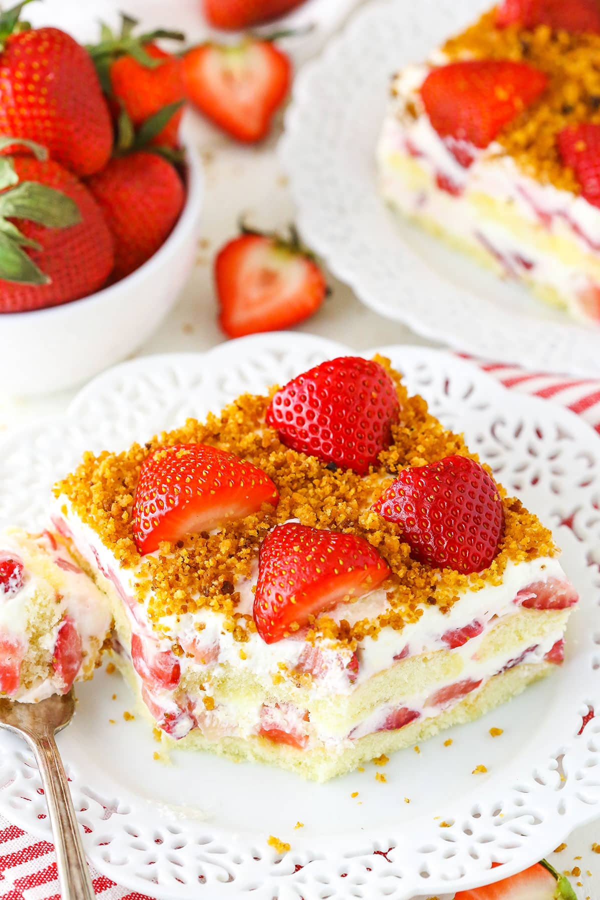 Slice of strawberry cake with graham cracker crumbs on top.