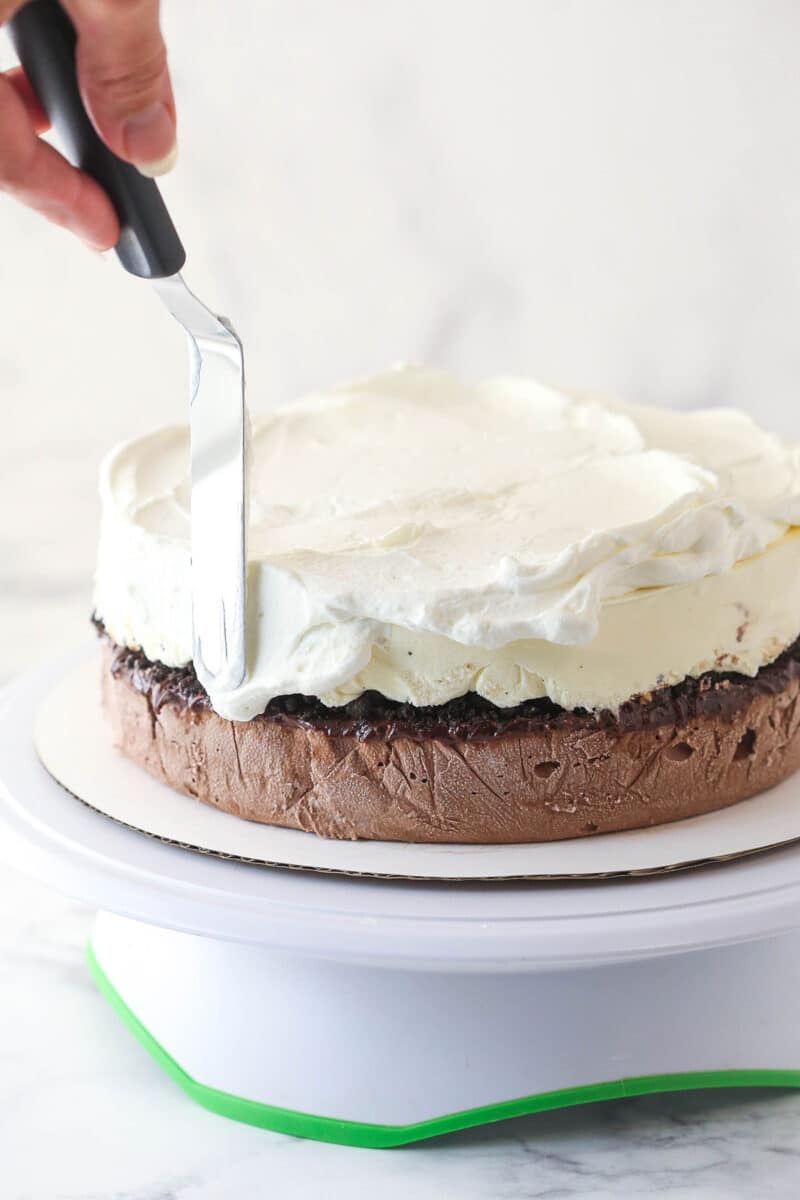 Adding whipped cream layer to ice cream cake.