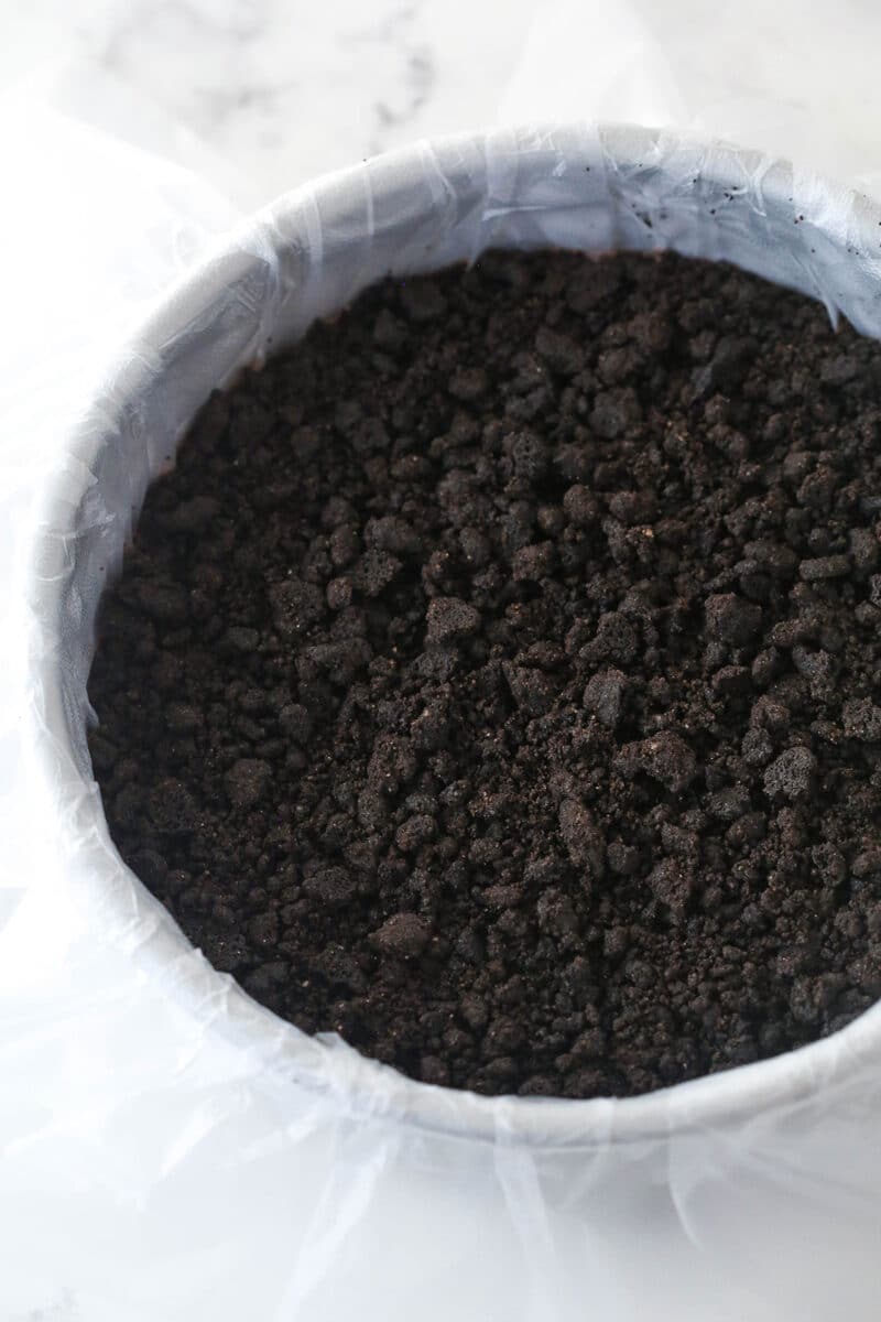 Oreo crust layer in cake pan.