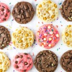 Four different kinds of cake mix cookies lined up on a marble countertop including flavors like chocolate, strawberry and butterscotch