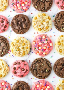 Four different kinds of cake mix cookies lined up on a marble countertop including flavors like chocolate, strawberry and butterscotch