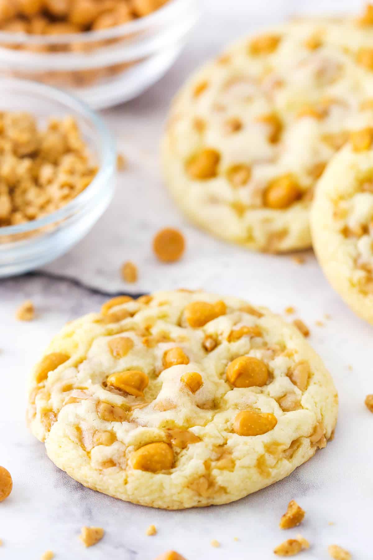 A toffee & butterscotch cake mix cookie on a kitchen countertop with more cookies behind it