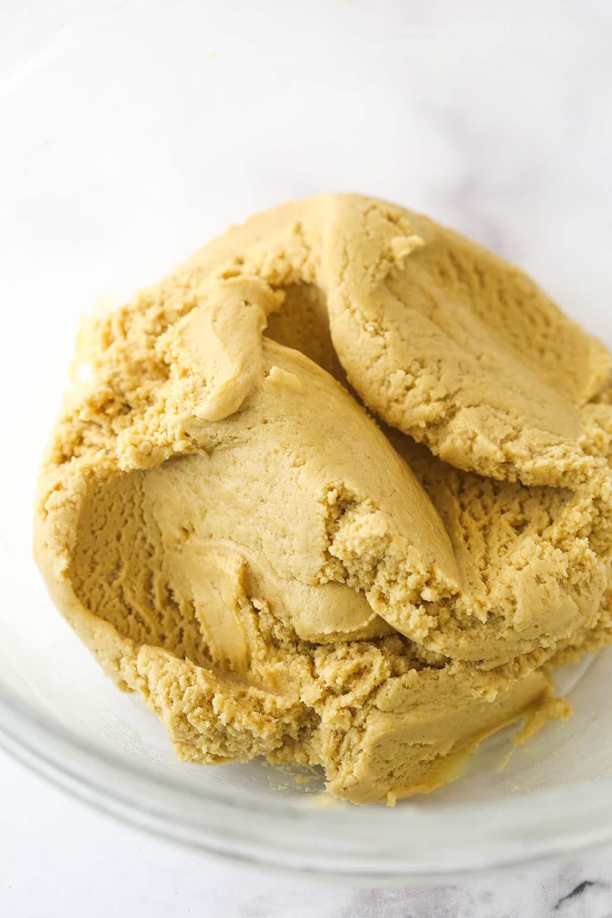 Cookie dough after the dry ingredients are added in a glass bowl.