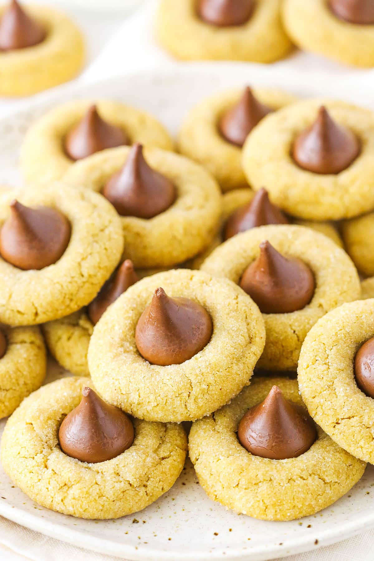These peanut butter blossom cookies are soft, chewy, and full of creamy peanut butter! A classic cookie recipe that's loved by all. A stack of peanut butter blossom cookies.