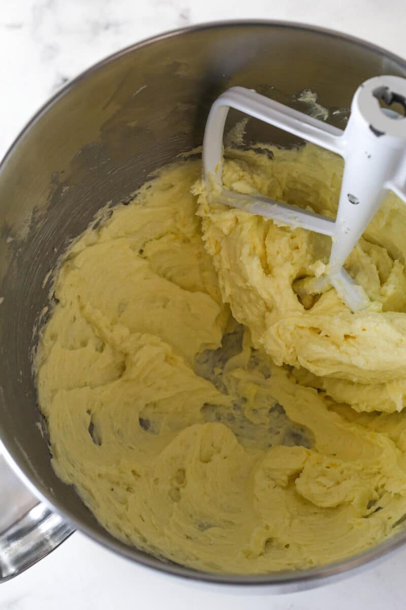 Spritz cookies are buttery, classic Christmas cookies made with a cookie press. This recipe is easy to make, with so many ways to decorate! Spritz cookie dough coming together with a mixer attachment in a mixing bowl.