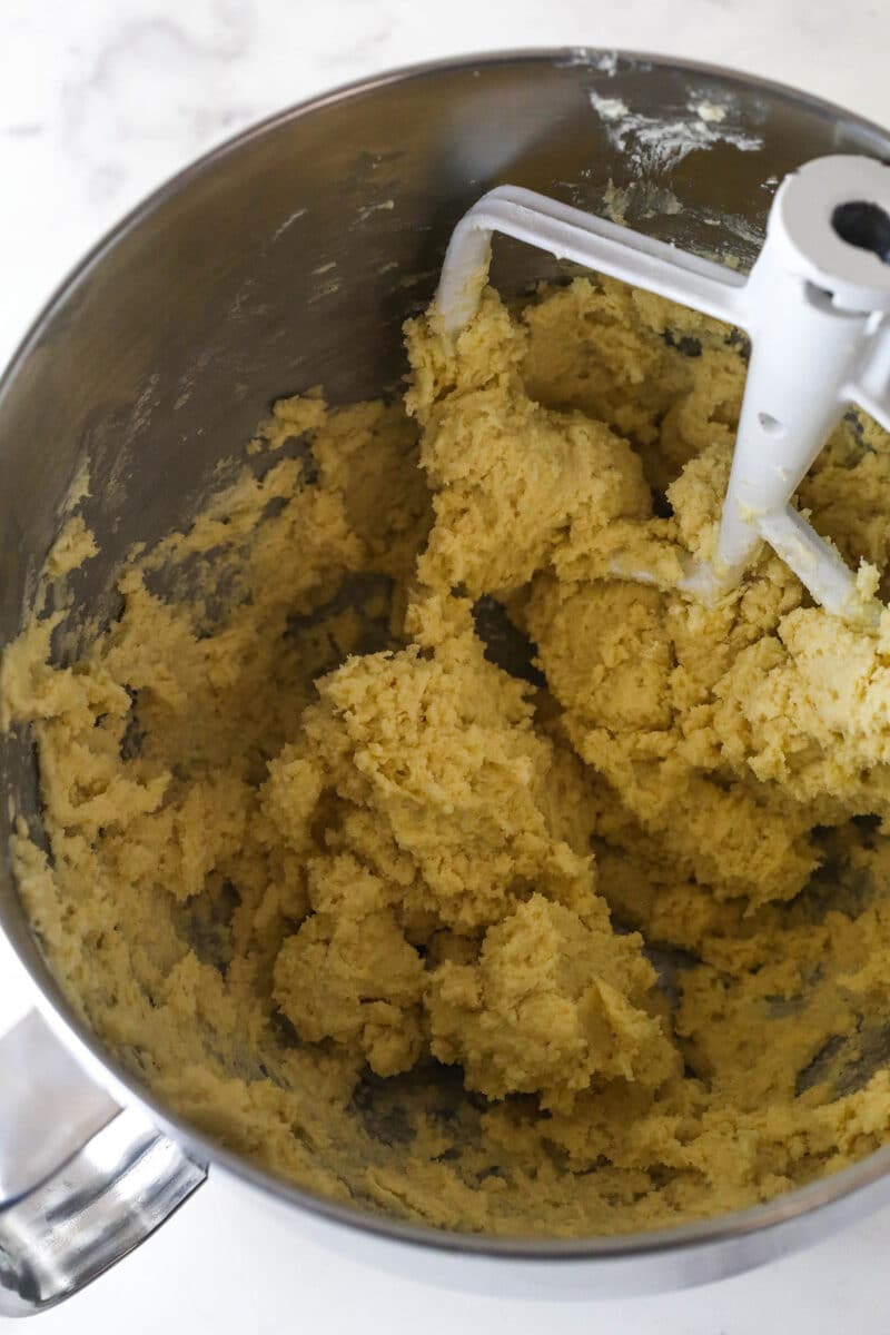 Spritz cookies are buttery, classic Christmas cookies made with a cookie press. This recipe is easy to make, with so many ways to decorate! Spritz cookie dough with a mixer attachment in a mixing bowl.