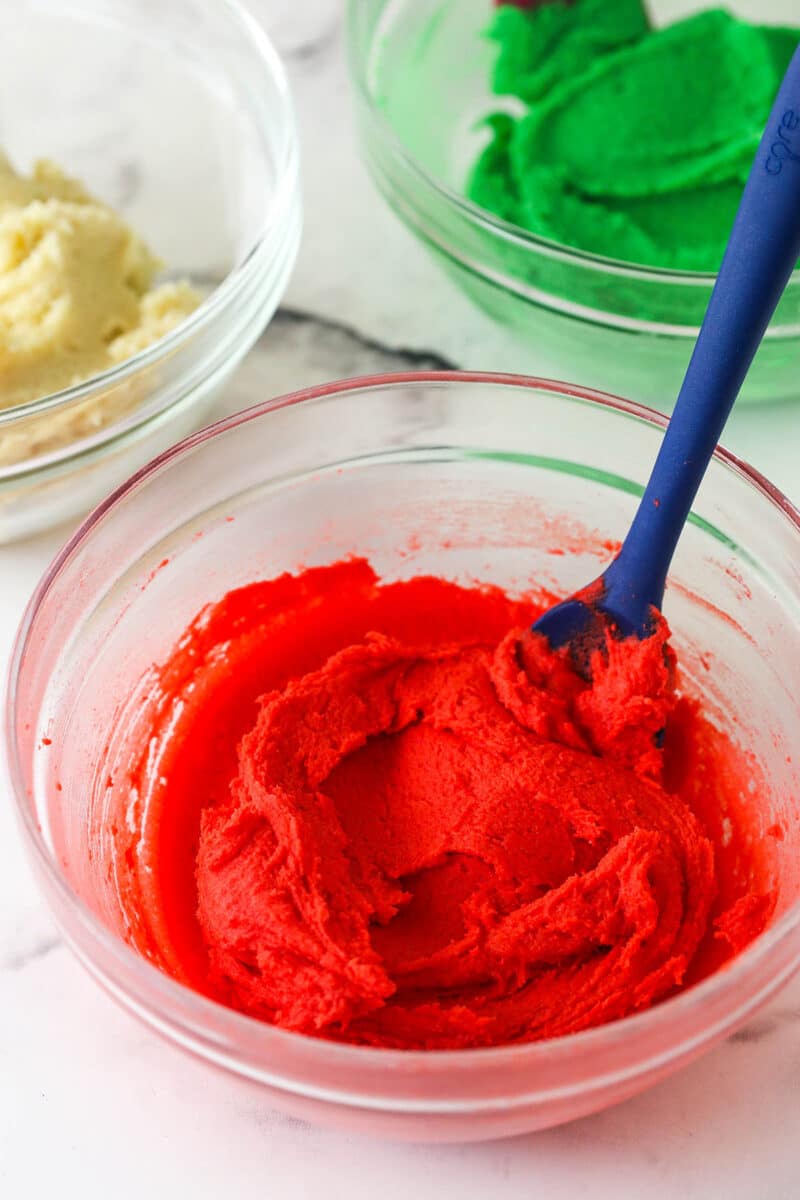 Spritz cookies are buttery, classic Christmas cookies made with a cookie press. This recipe is easy to make, with so many ways to decorate! Spritz cookie dough colored bright red in a mixing bowl.
