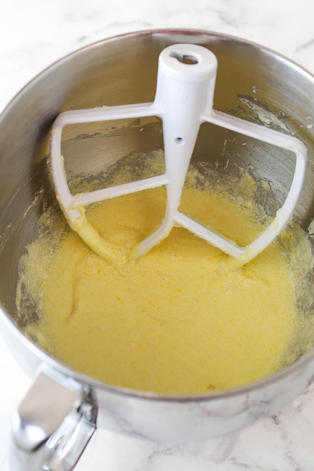 Overhead view of eggs combined with batter in a large mixing bowl