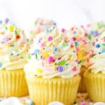 Close up of vanilla cupcakes with vanilla frosting and rainbow sprinkles