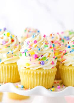 Close up of vanilla cupcakes with vanilla frosting and rainbow sprinkles