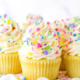 Close up of vanilla cupcakes with vanilla frosting and rainbow sprinkles