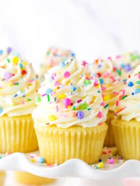 Close up of vanilla cupcakes with vanilla frosting and rainbow sprinkles