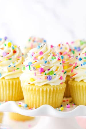 Close up of vanilla cupcakes with vanilla frosting and rainbow sprinkles