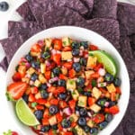 overhead image of berry fruit salsa in white bowl with blue tortilla chips
