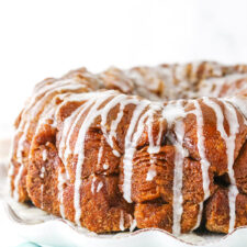 Side view of monkey bread with a glaze drizzle on a white plate.