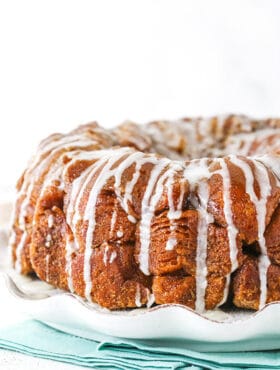 Side view of monkey bread with a glaze drizzle on a white plate.