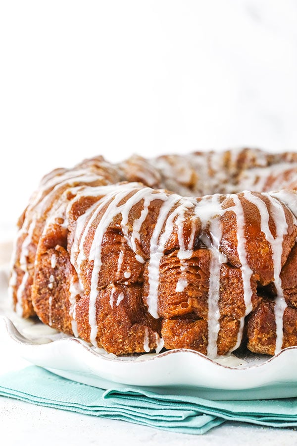 Side view of monkey bread with a glaze drizzle on a white plate.