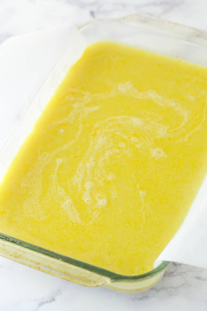 Easily the best homemade lemon bars ever! Perfectly sweet and tart, with a buttery cookie crust and creamy, crack-free lemon curd filling. unbaked filling in glass pan