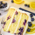 A slice of lemon cake dotted with fresh blueberries on a white plate.