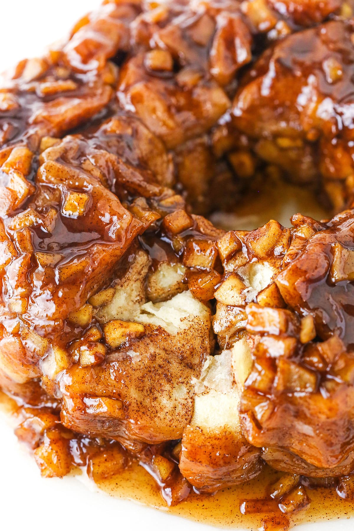 Overhead view of Apple Fritter Monkey Bread with a few pieces removed showing bread texture on a white cake stand