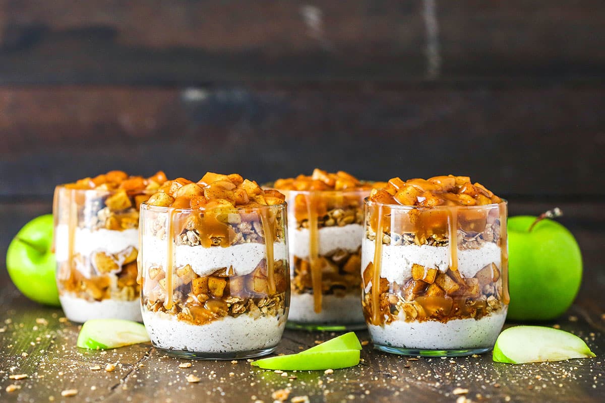 These Caramel Apple Trifles are the perfect apple treat for fall - no bake, super easy and full of cinnamon! Side view of 4 Caramel Apple Trifles in glass cups on a wooden background