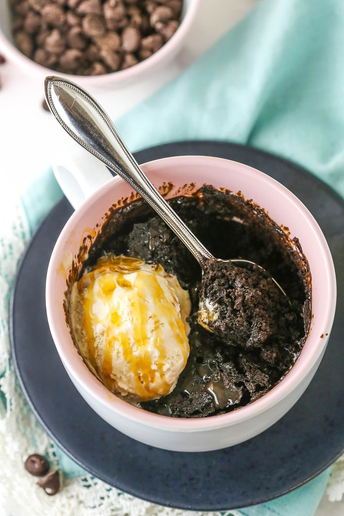 Overhead view of a Chocolate Mug Cake with a scoop of ice cream and a scoop of cake missing in a pink bowl