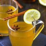 Two Cups of Hot Toddy Garnished with a Lemon Slice, a Cinnamon Stick and an Anise Star