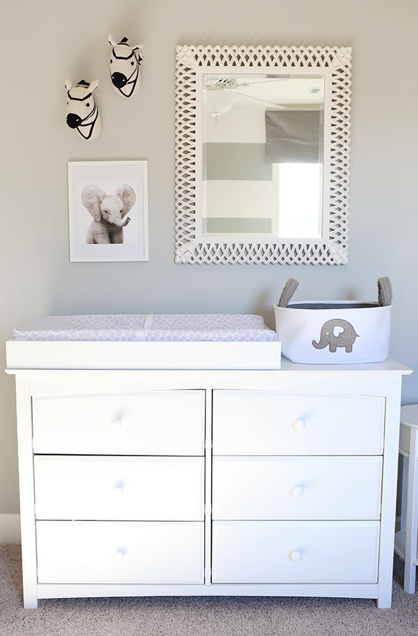 A White Dresser with a Changing Table on Top and a Mirror on the Wall Above