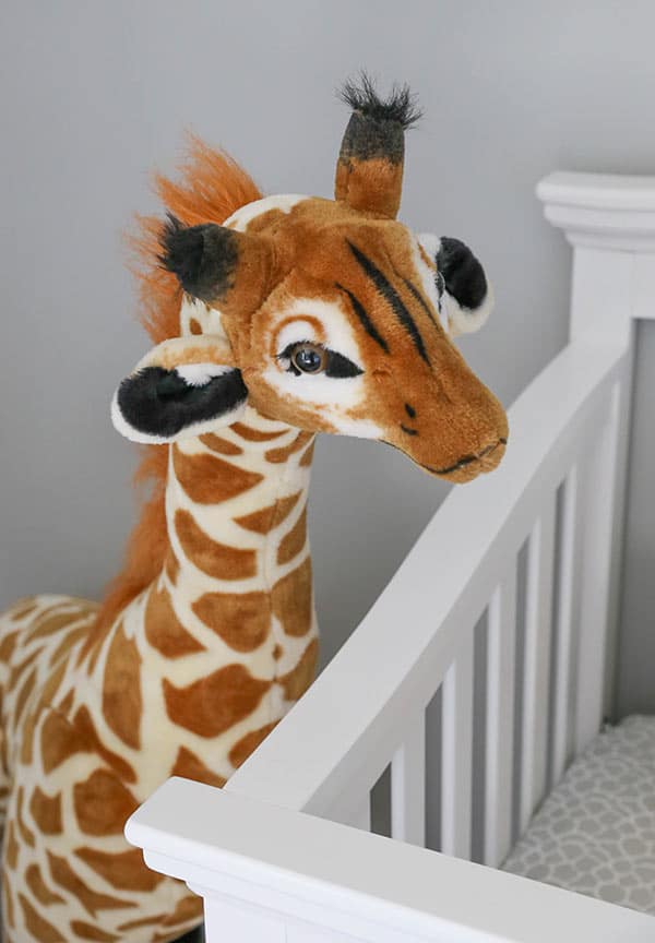 A Large Stuffed Giraffe Peeking Over Ashton's Crib