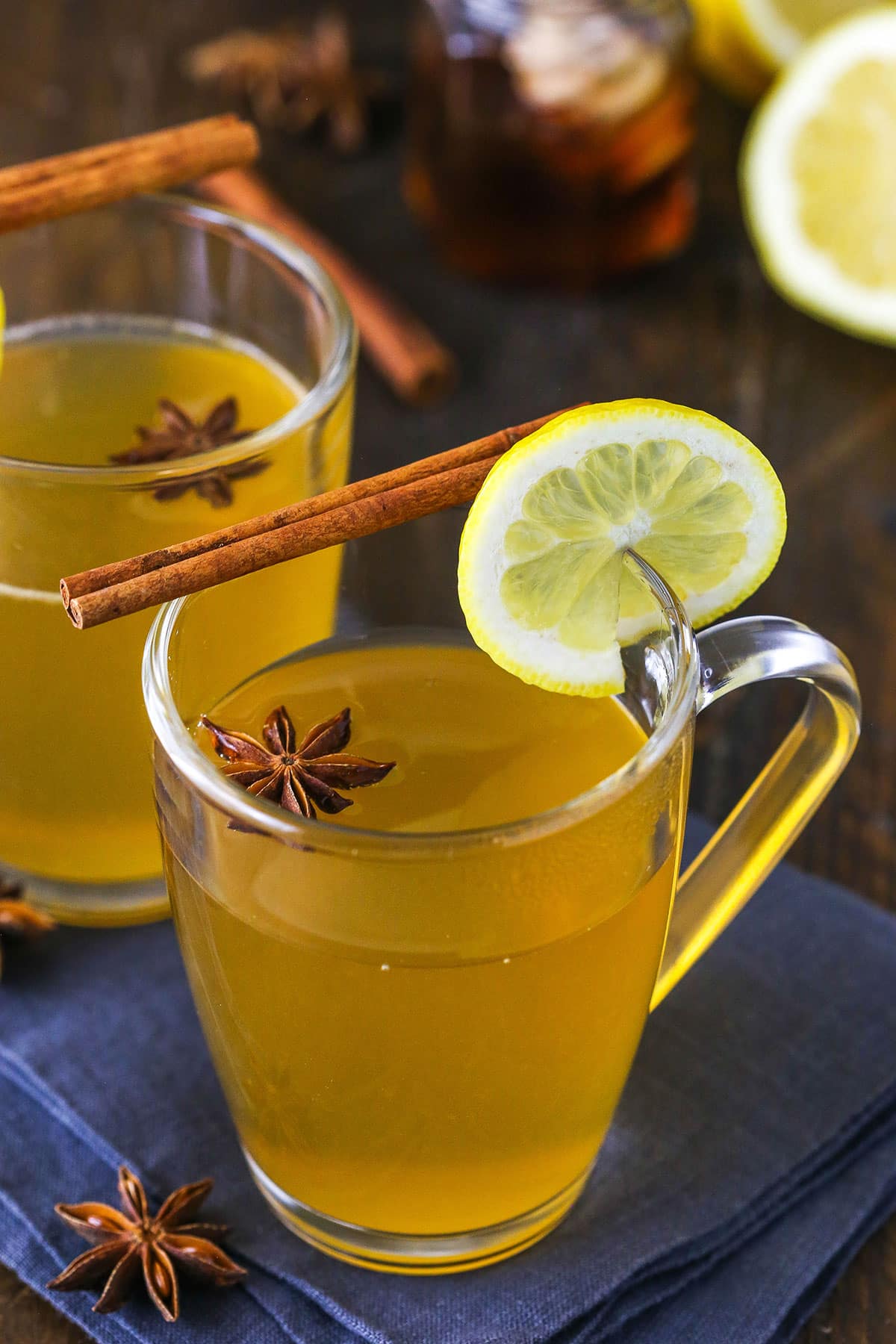 Two Cups of Hot Toddy Garnished with a Lemon Slice, a Cinnamon Stick and an Anise Star