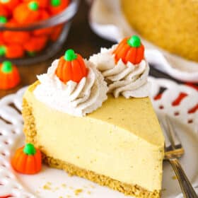 A slice of no bake pumpkin cheesecake topped with swirls of whipped cream on a plate.