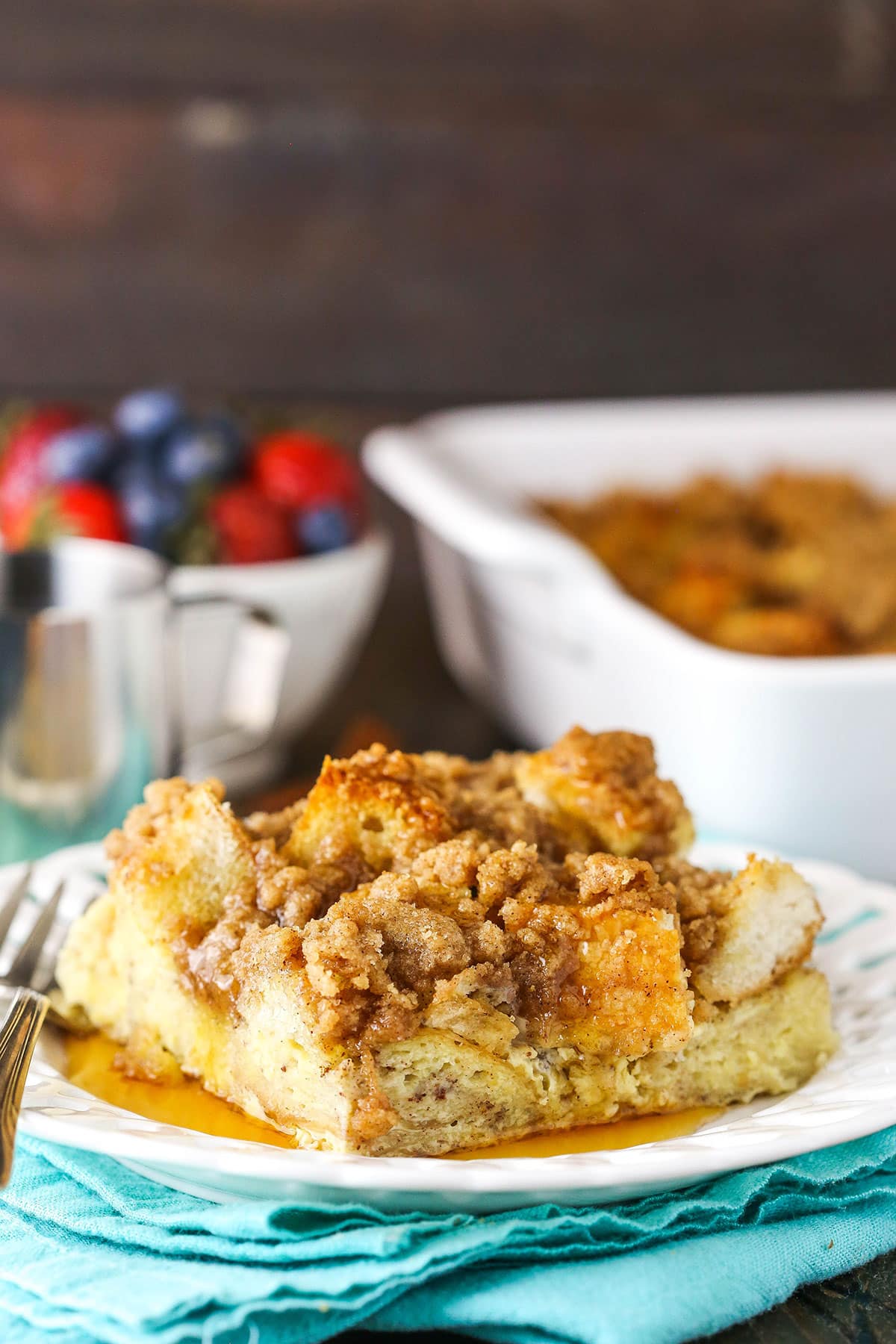 A slice of Overnight Cinnamon French Toast Casserole with syrup on a white plate