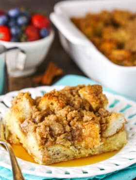 A slice of Overnight Cinnamon French Toast Casserole with syrup on a white plate