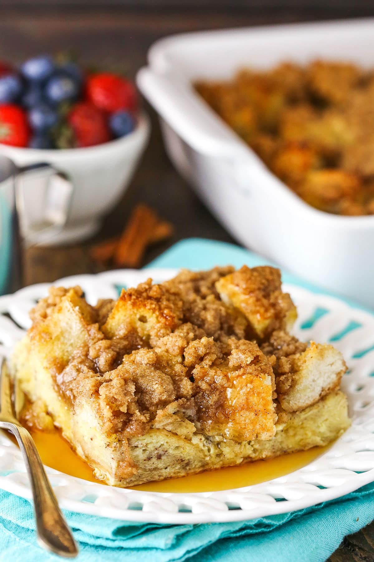 A slice of Overnight Cinnamon French Toast Casserole with syrup on a white plate