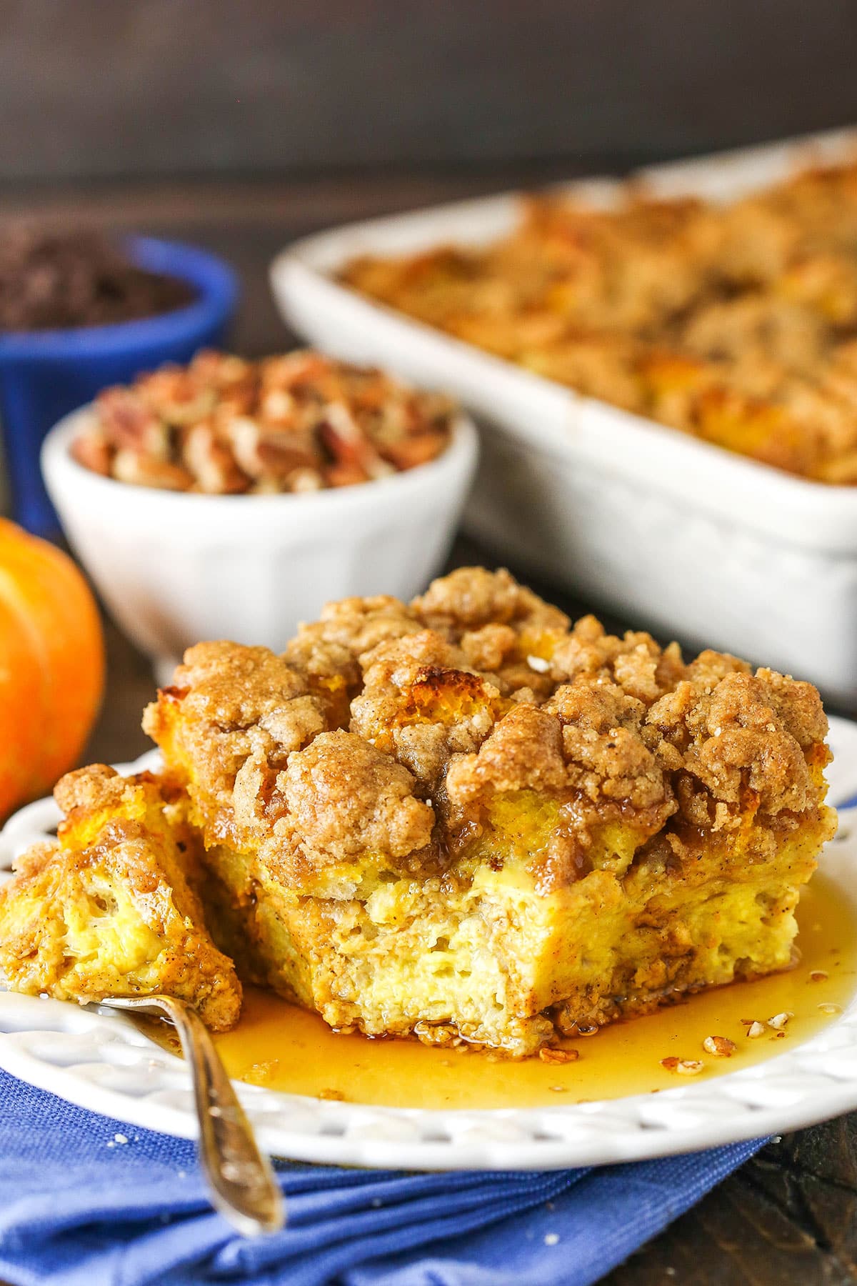 Side view of a square serving of Overnight Pumpkin Spice French Toast Casserole with a bite taken out on a white plate with a fork