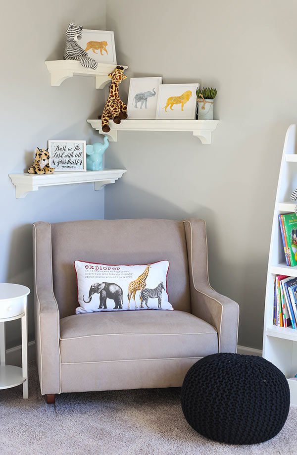 A Taupe Rocker with Three White Floating Shelves on the Wall Above it