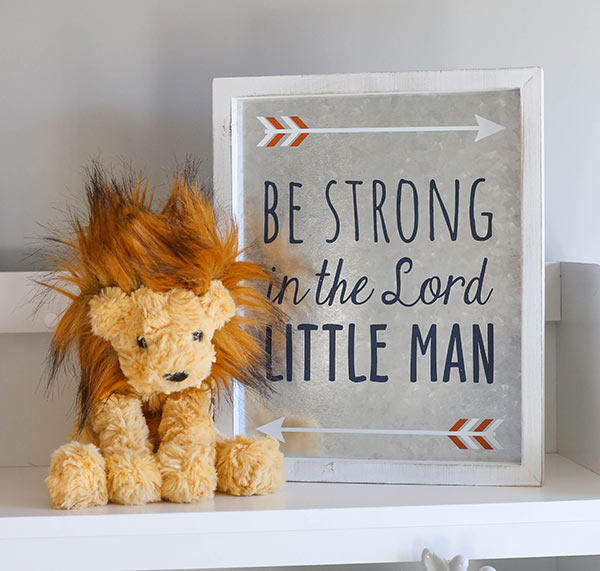 A Little Stuffed Lion on a Shelf Next to "Be Strong in the Lord" Decor