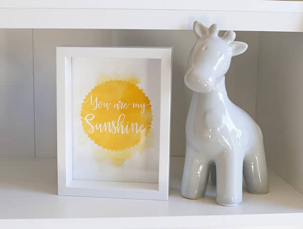 A Ceramic Giraffe Beside a Print that Reads "You are my Sunshine"