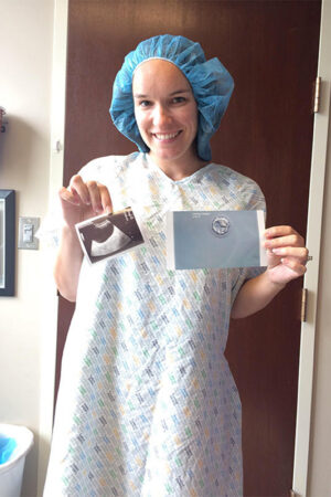 Lindsay in a Hospital Gown Holding Photo of Her Embryo