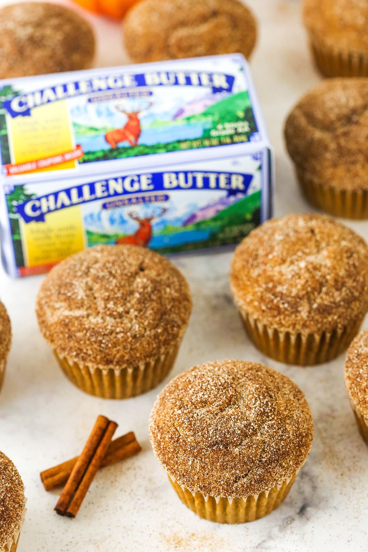 cinnamon sugar pumpkin muffins next to cinnamon sticks and challenge butter