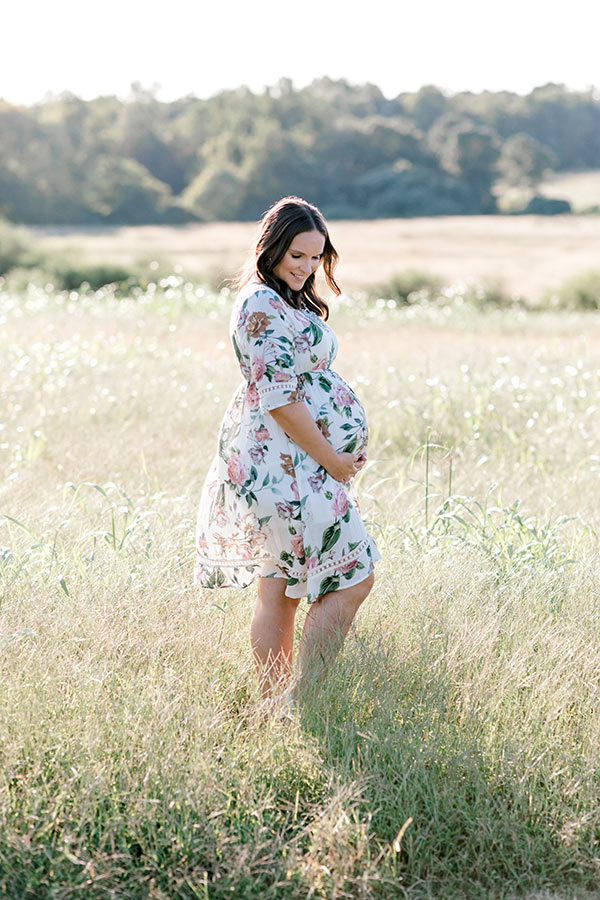 Lindsay standing in field cradling belly