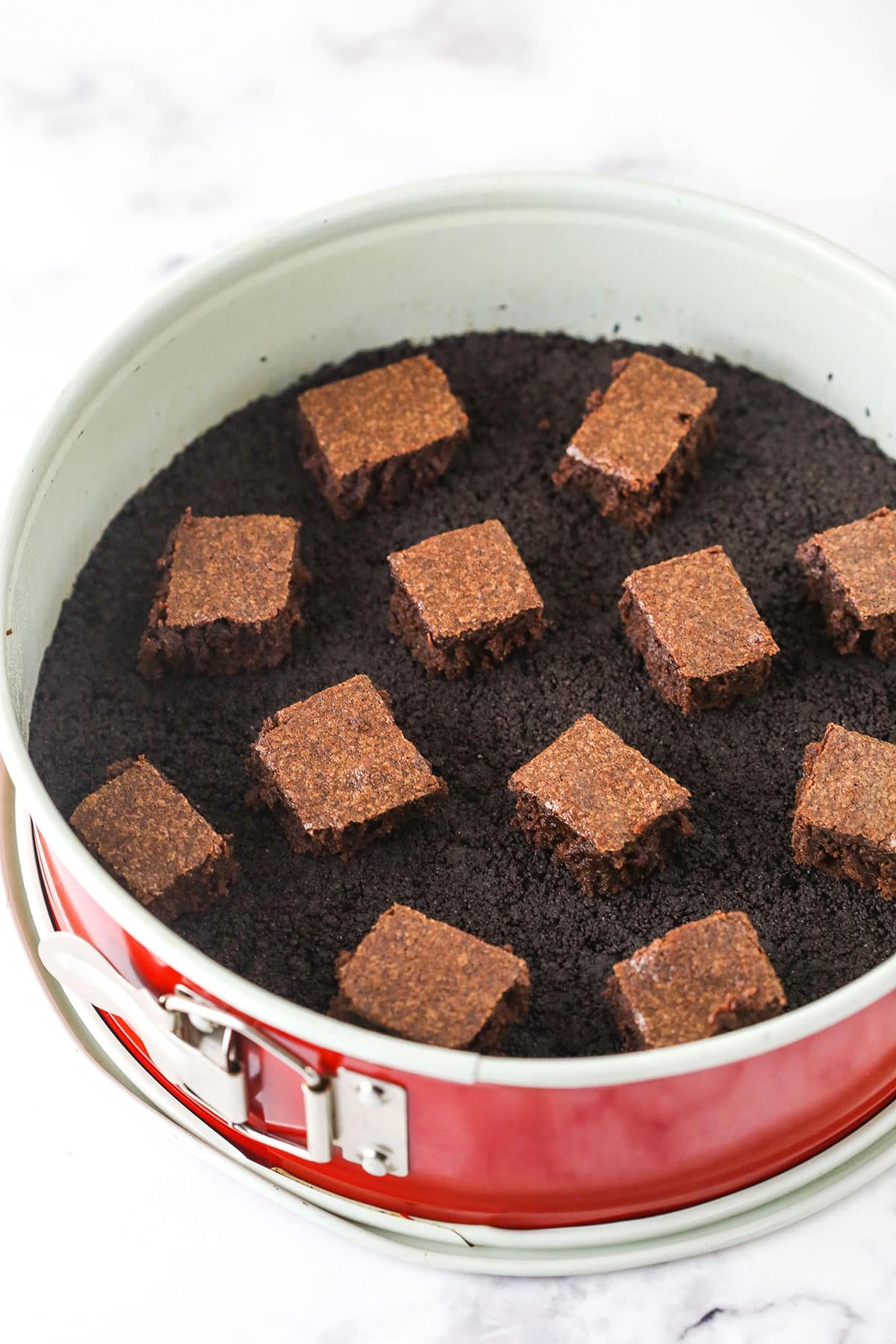 chunks of brownie sitting in the crust in the springform pan