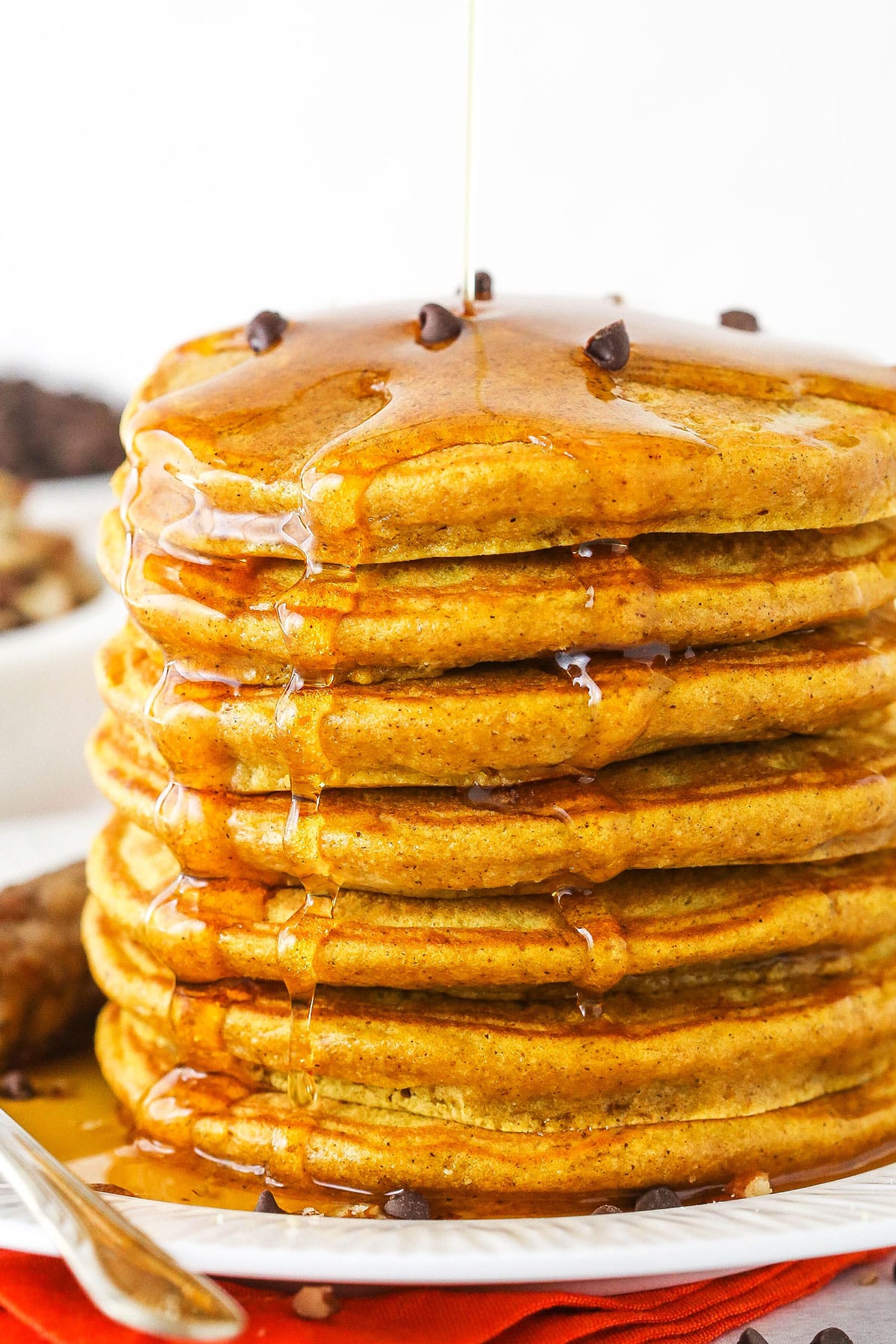 Seven super fluffy pumpkin pancakes stacked on a plate.