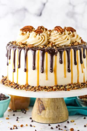 Side view of a full Turtle Chocolate Layer Cake on a white cake stand