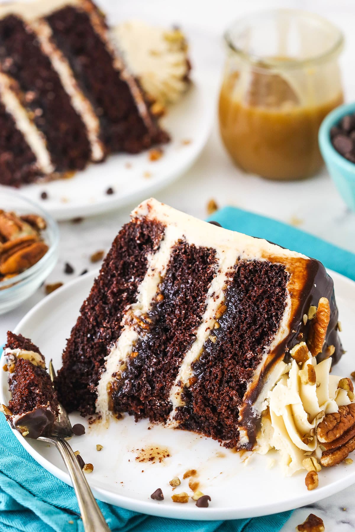 A slice of Turtle Chocolate Layer Cake on it's side with a bite removed on a white plate