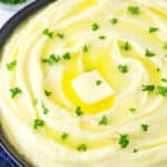 Close-up of fluffy mashed potatoes with butter and fresh parsley.