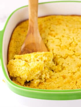 A Wooden Spoon Scooping out a Serving of Creamy Cornbread Casserole