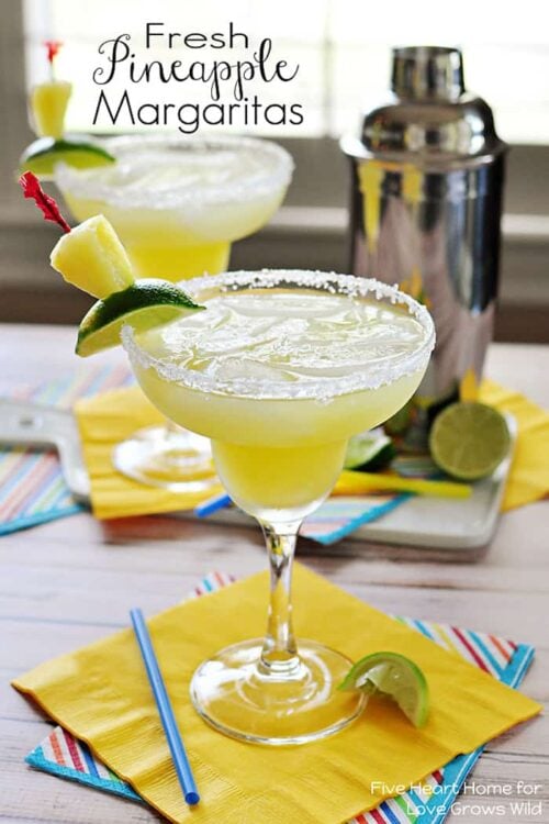 Two Frozen Pineapple Margaritas Garnished With Lime Slices and Chunks of Pineapple