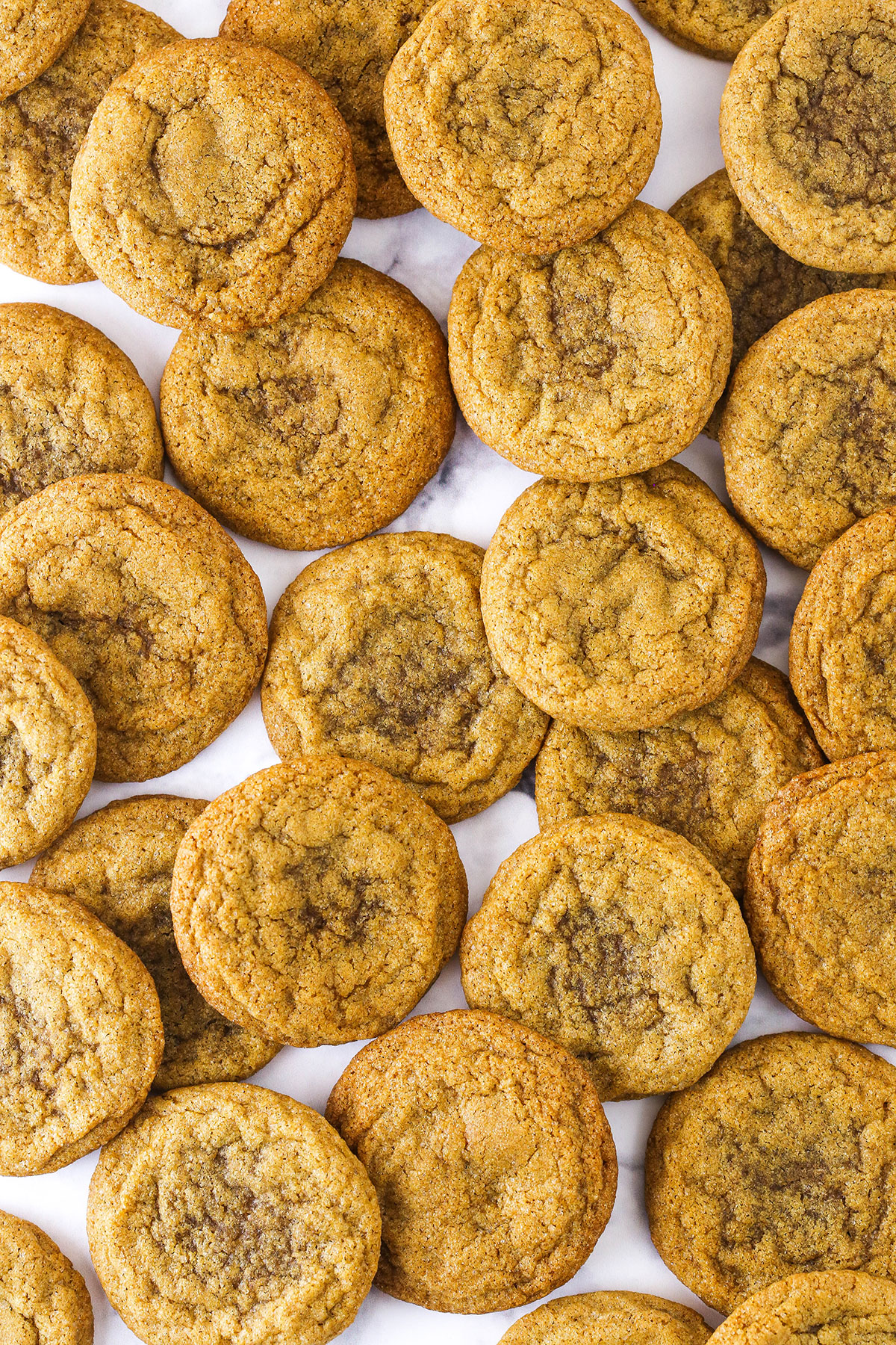 Molasses cookies arranged on a white marble surface.